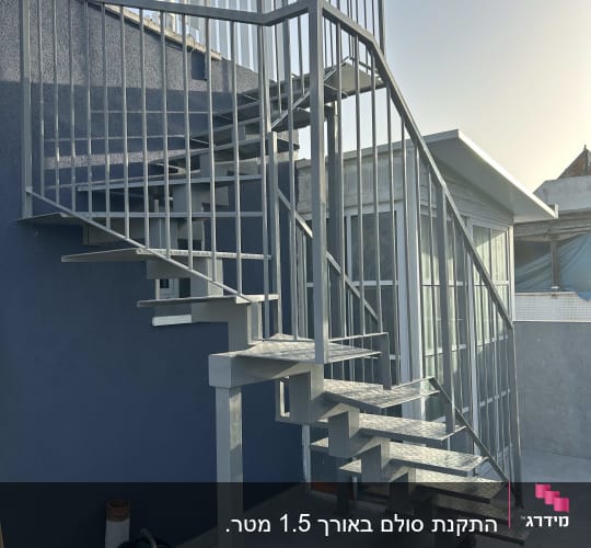 מדרגות מתכת עם מעקה על רקע קיר כחול